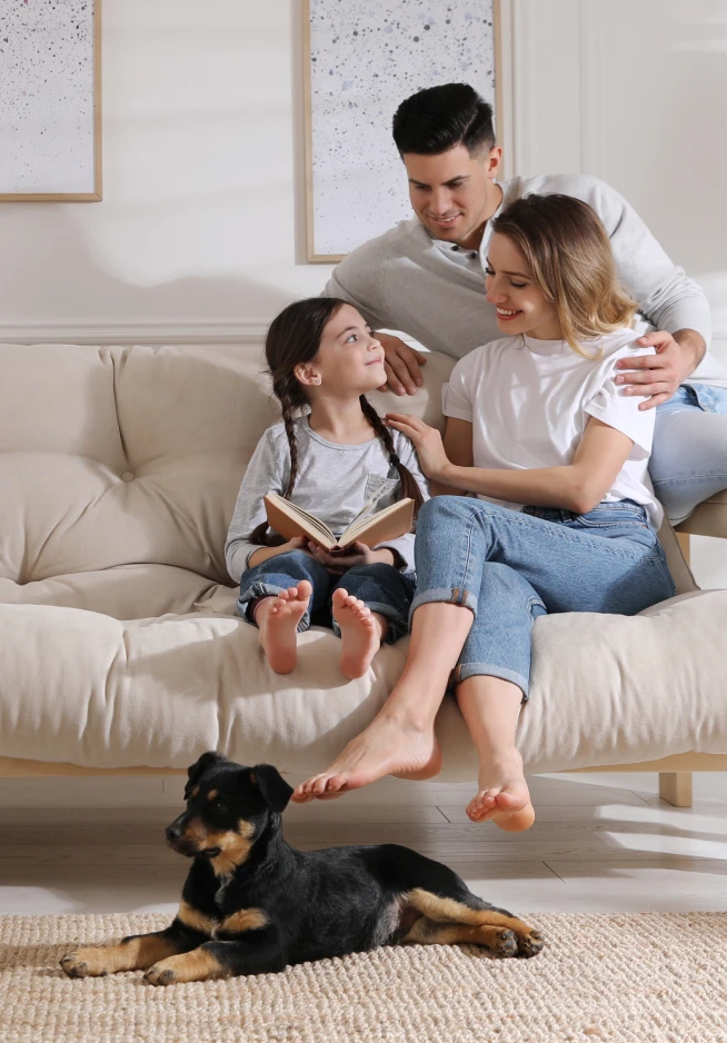 Família sentada num sofá com um cão aos seus pés