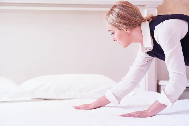 empregada de hotel a alisar lençóis de cama