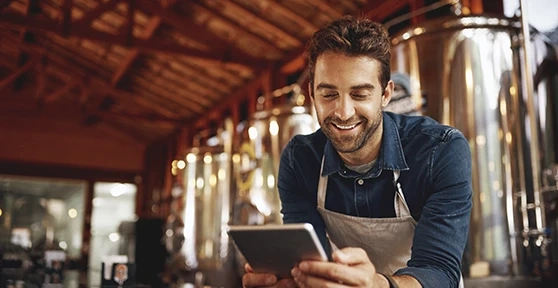 Man in an apron using a tablet in his business