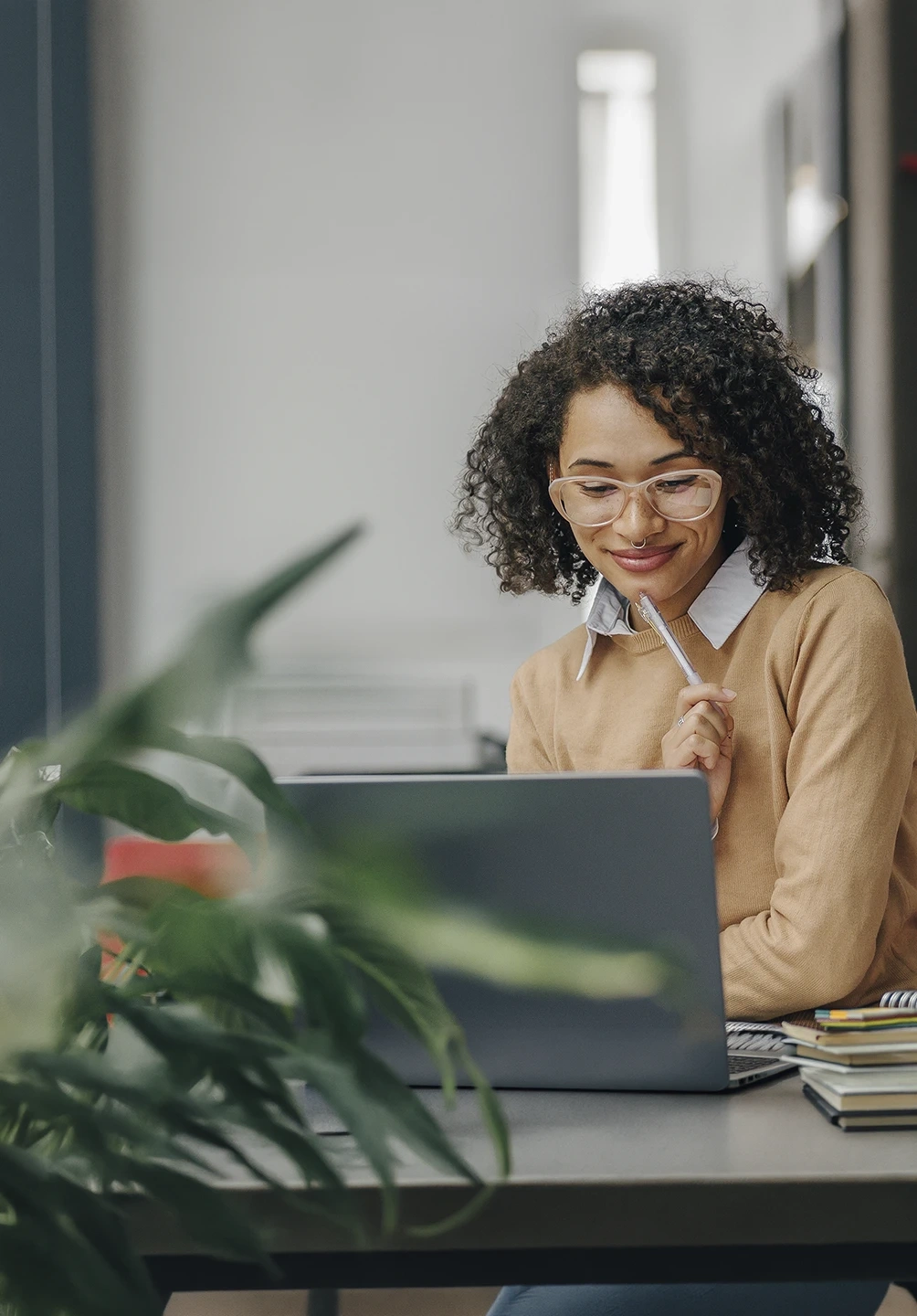 Woman smiles while working on her laptop at a desk