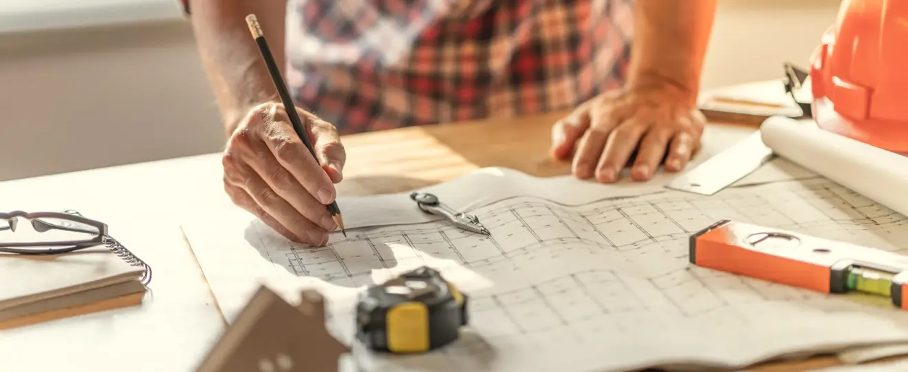 Arquiteto a desenhar numa planta de construção com ferramentas