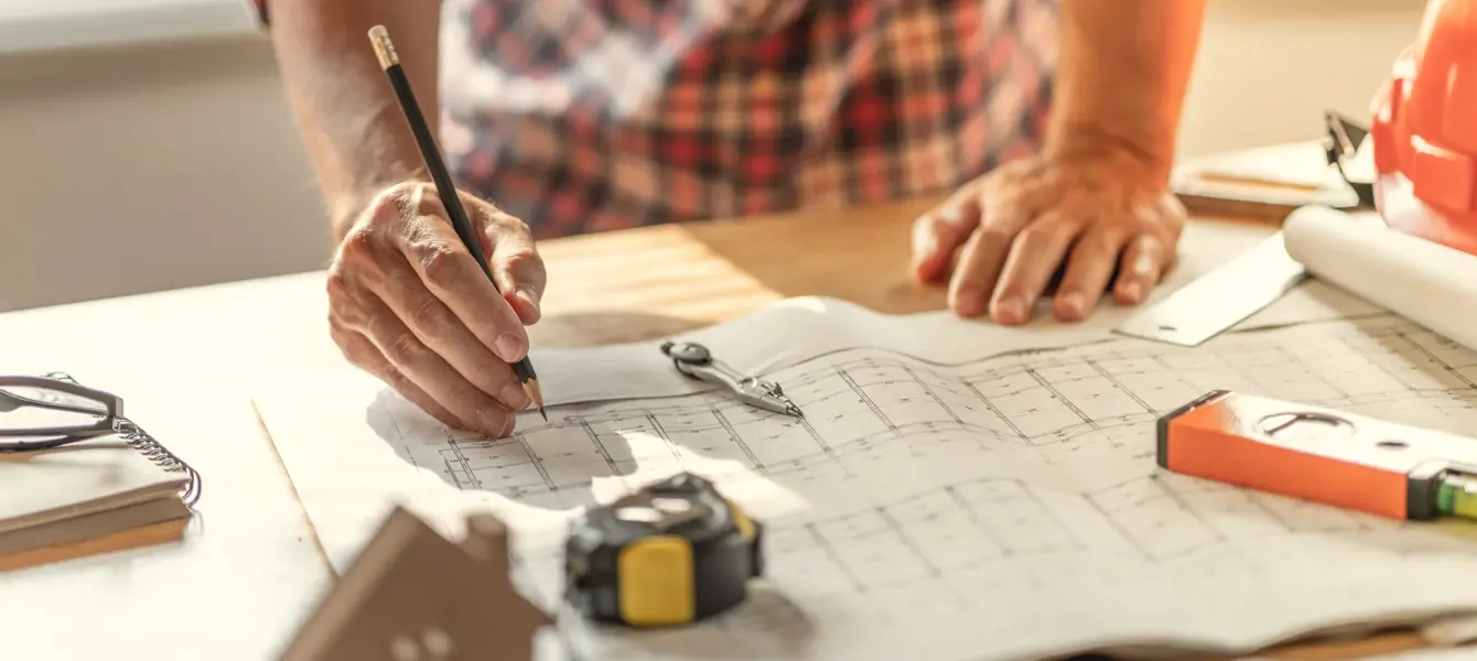 Arquiteto a desenhar numa planta de construção com ferramentas