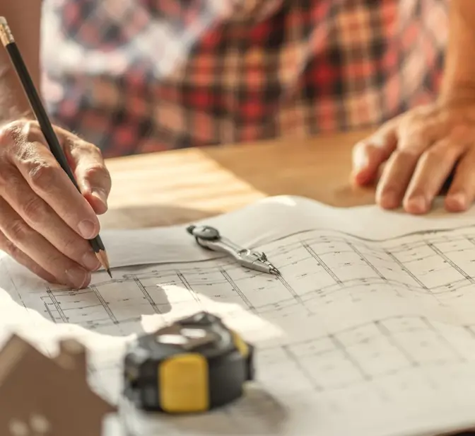 Arquiteto a desenhar numa planta de construção com ferramentas