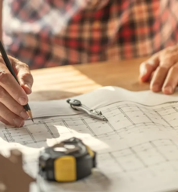 Arquiteto a desenhar numa planta de construção com ferramentas