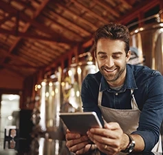 Man in an apron using a tablet in his business