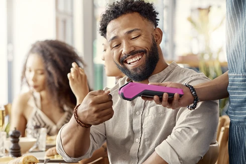 homem a pagar conta num restaurante, usando cartão contactless num TPA