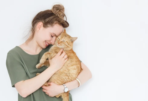 Rapariga de t-shirt verde com a cabeça encostada no gato que tem ao colo