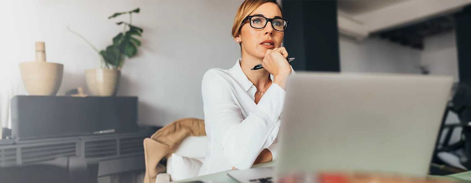 senhora com ar pensativo, em frente ao computador