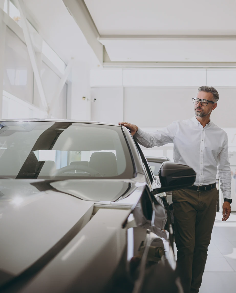 homem, num stand, a tocar num carro novo