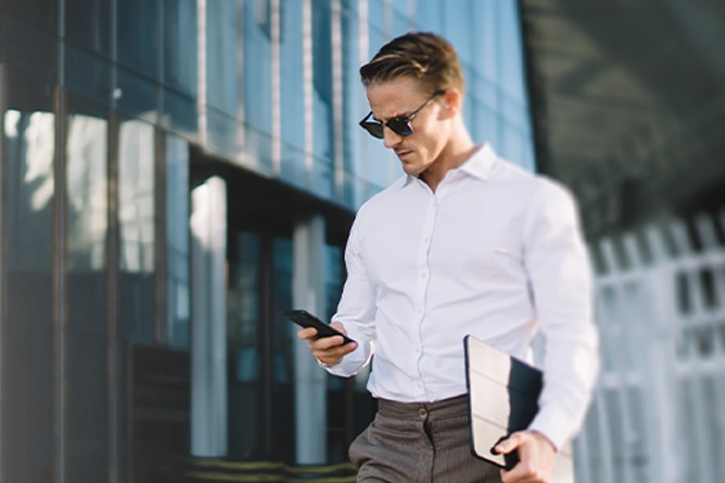 man in a suit, standing, looking at phone