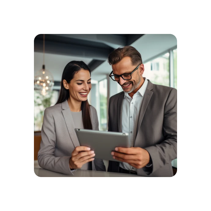 man and woman, in suits, watching a tablet