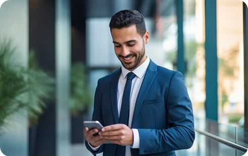 homem de fato, sorridente, a consultar o telemóvel