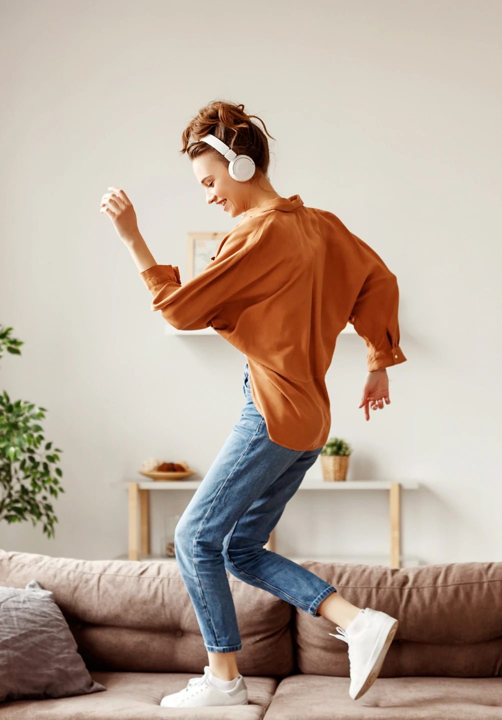 girl dancing on the sofa with headphones on