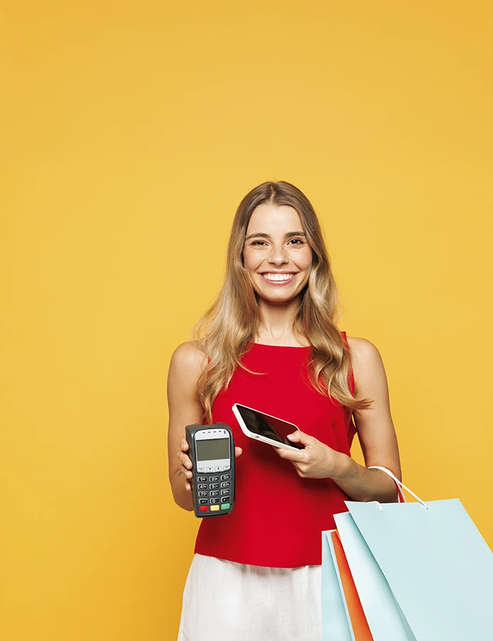 senhora sorridente com sacos de compras, telemóvel e um TPA