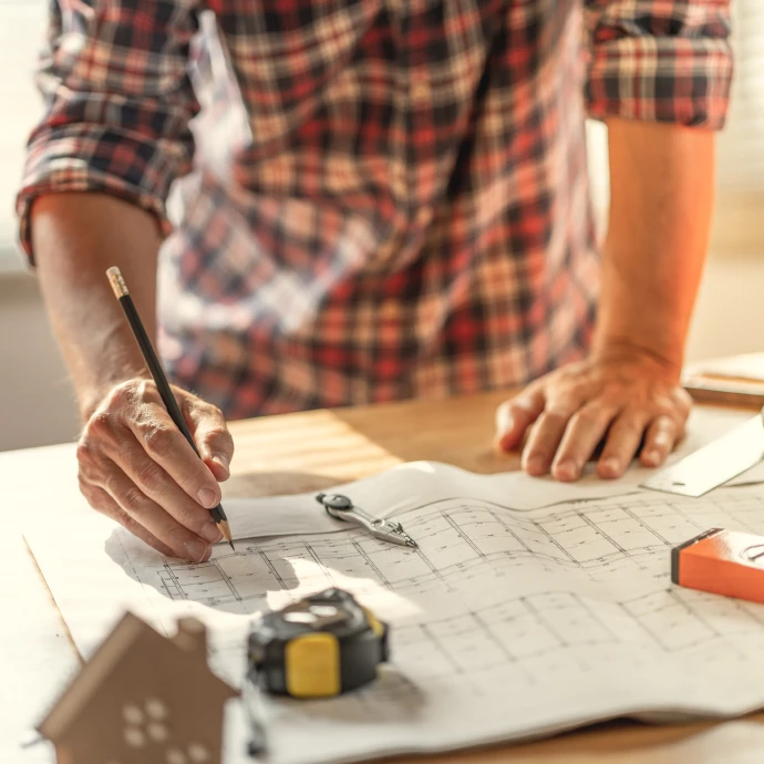 Pessoa a desenhar um projecto técnico sobre uma planta de construção