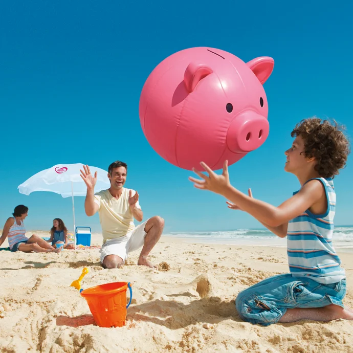 Família na praia, com guarda-sol Millennium, e bóia cor-de-rosa com formato de porquinho mealheiro