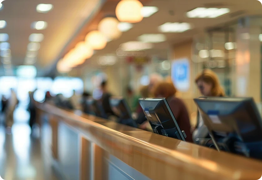 imagem desfocada de grande bancada com vários computadores e pessoas a trabalhar