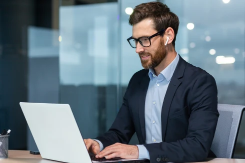 homem com óculos e auricular, a trabalhar num computador