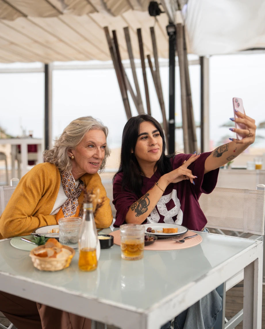 Custódia Gallego, a representar a personagem Fernanda Guimarães, e uma jovem a tirarem uma selfie, num bar de praia