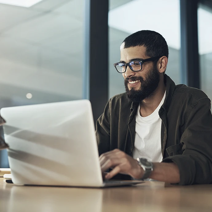 Rapaz com o computador aberto e a trabalhar sorridente