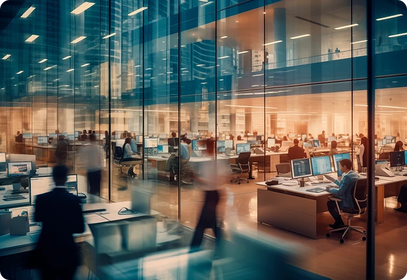 escritório grande, com paredes de vidro, várias secretárias com pessoas a trabalhar