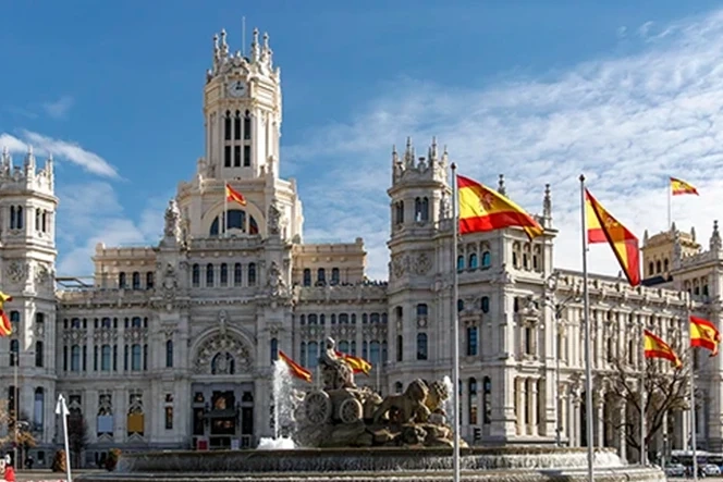 Cibeles Palace in Madrid with the Spanish flag flying against a blue sky