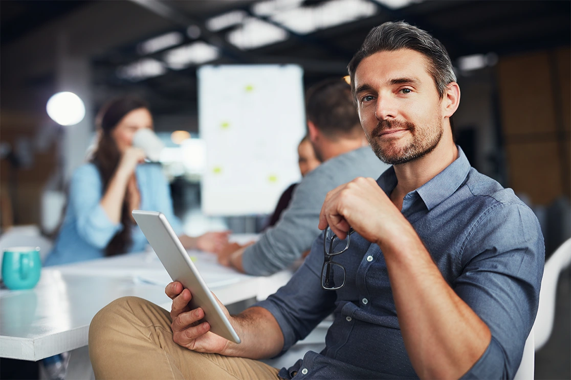 man sitting and smilling, holding tablet