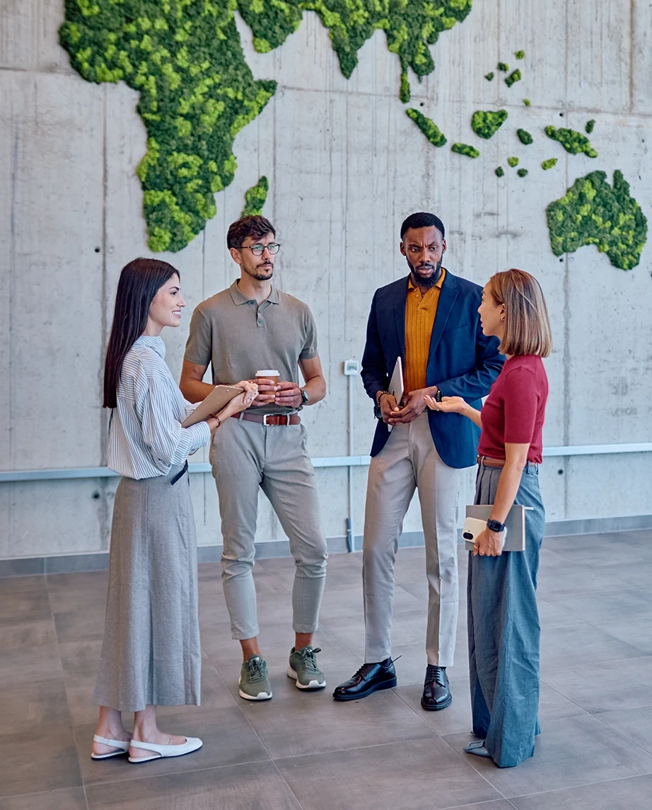 Group of colleagues talking in front of a green world map