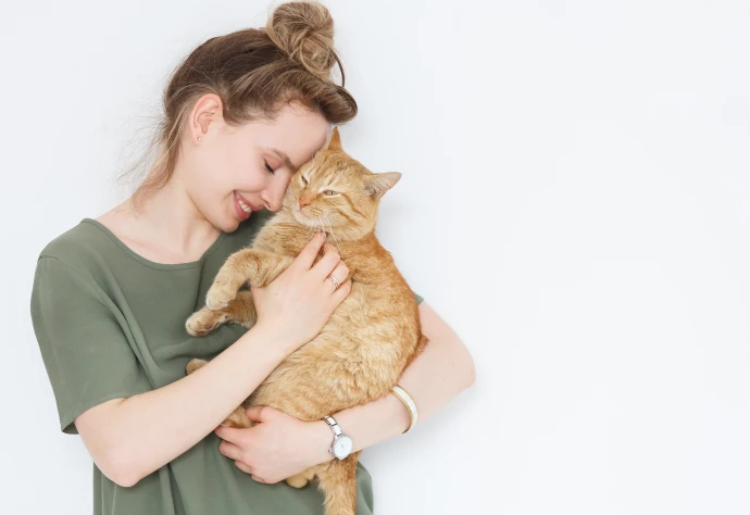 Rapariga de t-shirt verde com a cabeça encostada no gato que tem ao colo