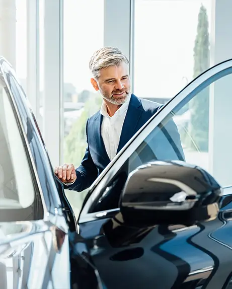 gentleman at the car dealership, with a car door open, observing it