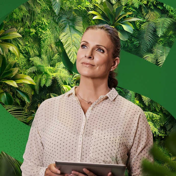 Mulher segura um tablet e olha para cima, com um fundo de plantas