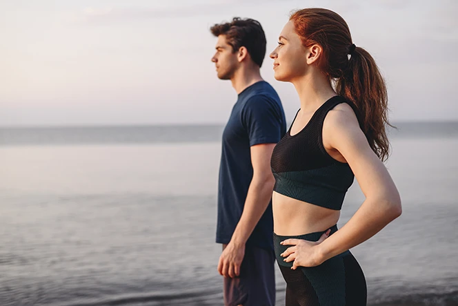 casal jovem, vestidos com roupa desportiva, à beira mar