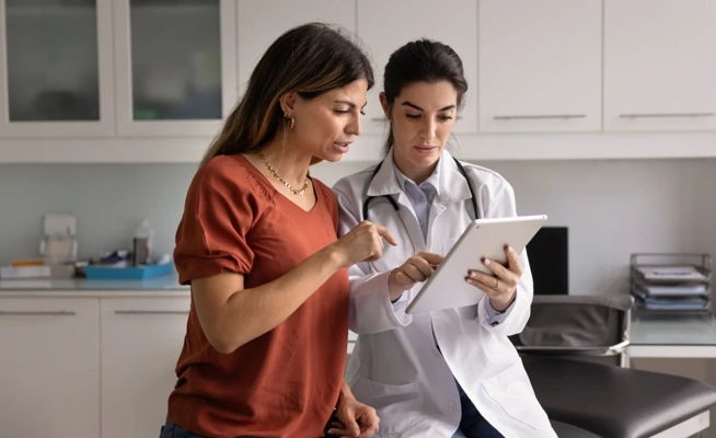 Médica a mostrar informação a uma paciente num tablet