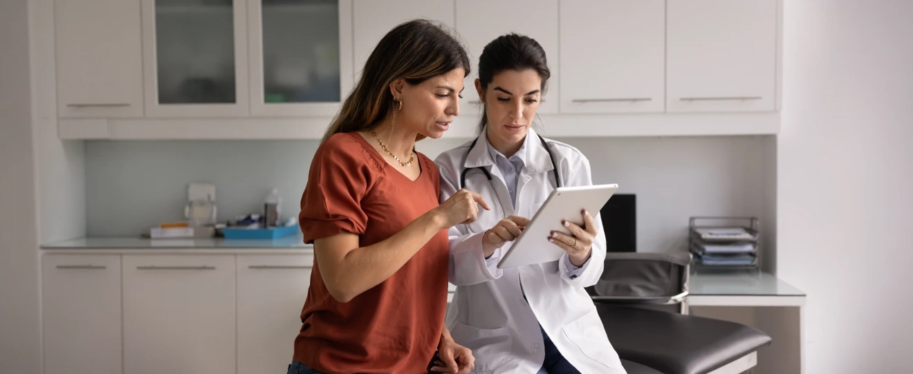 Médica a mostrar informação a uma paciente num tablet