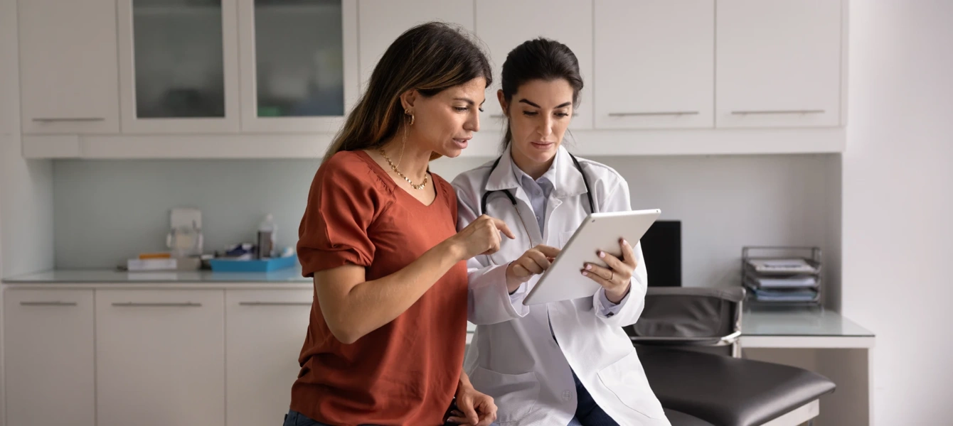 Médica a mostrar informação a uma paciente num tablet