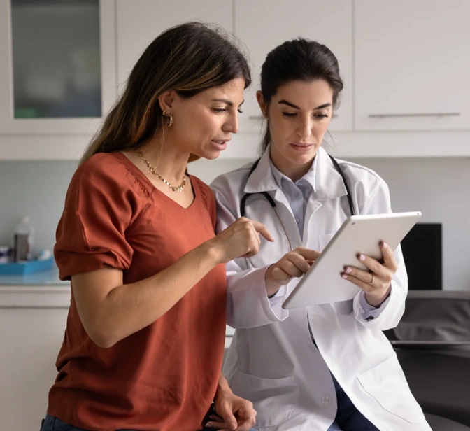 Médica a mostrar informação a uma paciente num tablet