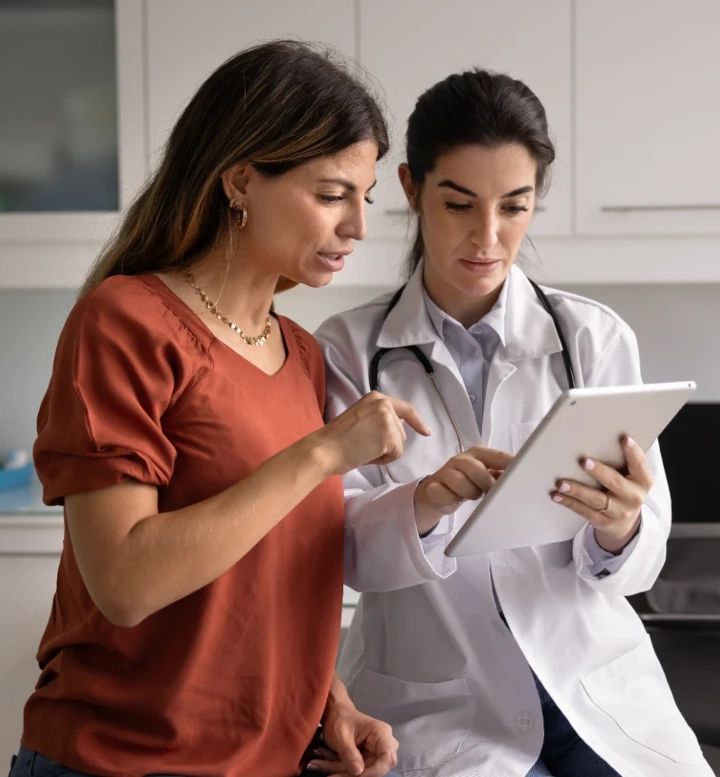 Médica a mostrar informação a uma paciente num tablet