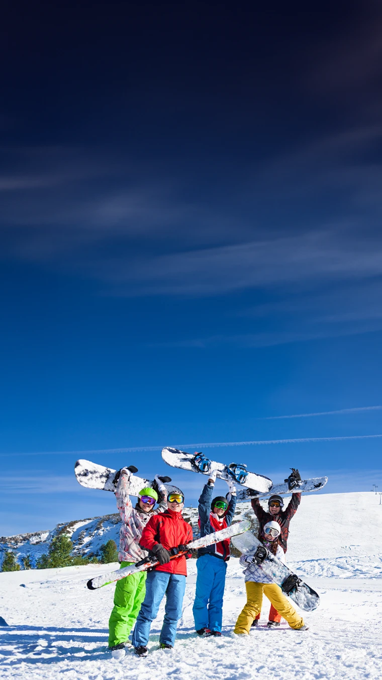 5 pessoas, numa montanha com neve, equipados e com pranchas de ski e snowboard