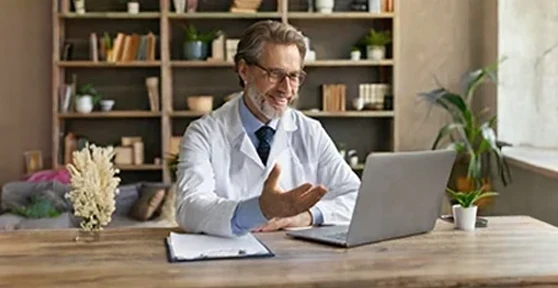 médico em frente a computador, em teleconsulta