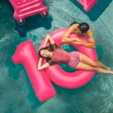 Casal relaxa em piscina com bóias em forma de 10