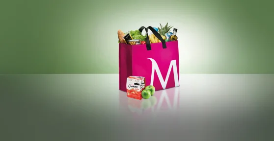 Saco de compras cerise, com o "M" de Millennium bcp desenhado, cheio de fruta, legumes e outra comida