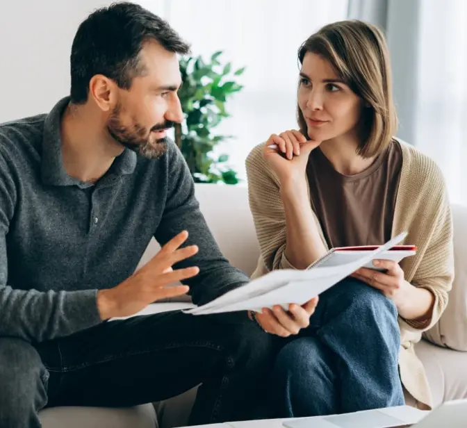 Casal a discutir documentos no sofá, homem a gesticular