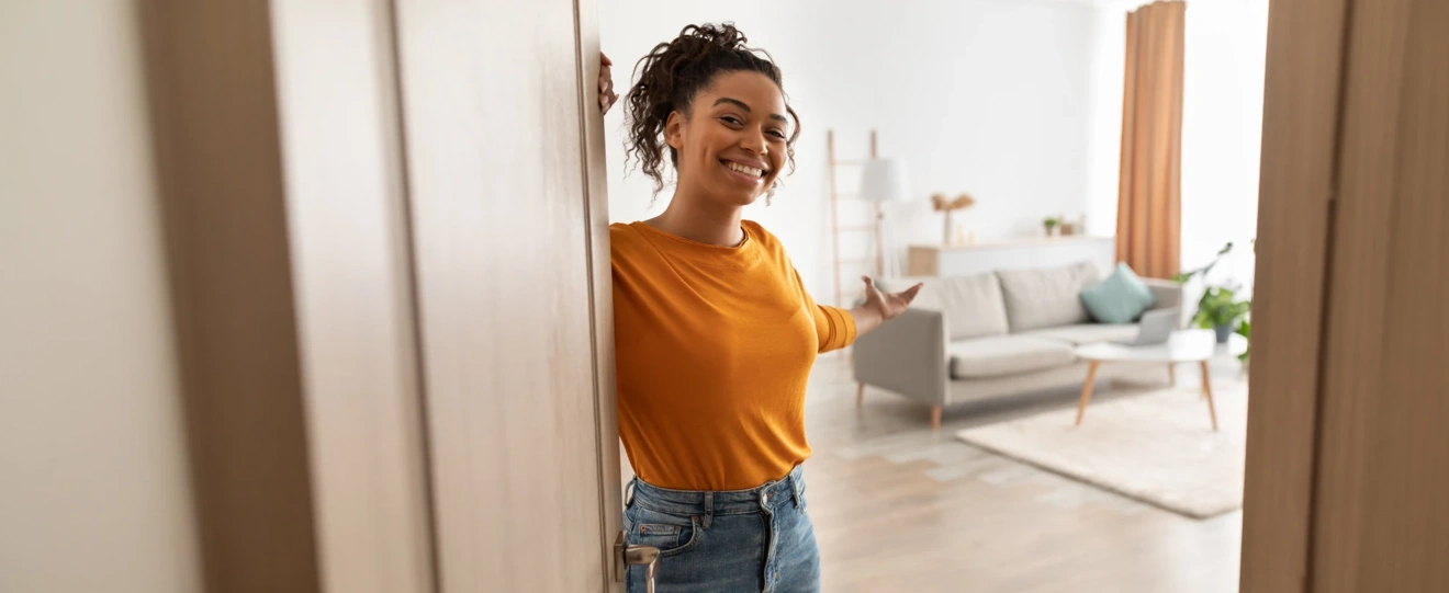 Mulher sorridente a abrir a porta de uma sala de estar moderna