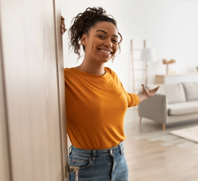 Mulher sorridente a abrir a porta de uma sala de estar moderna