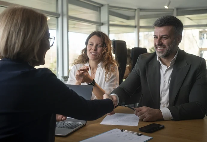 Casal em reunião de negócios a apertar a mão de uma consultora