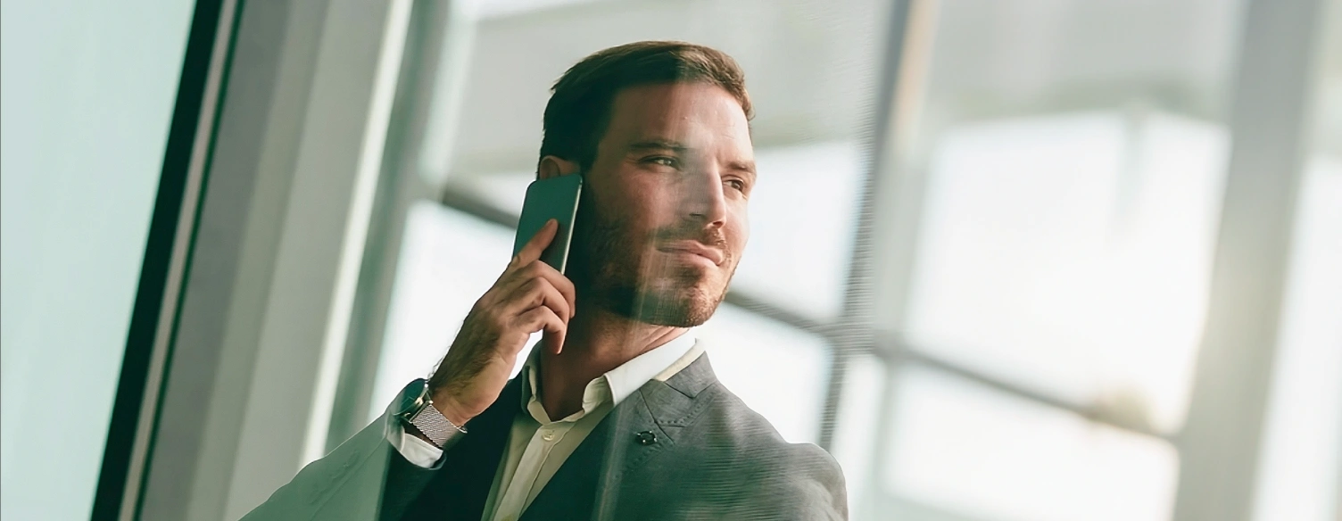 man in a suit and tie, talking on the phone, looking to the side