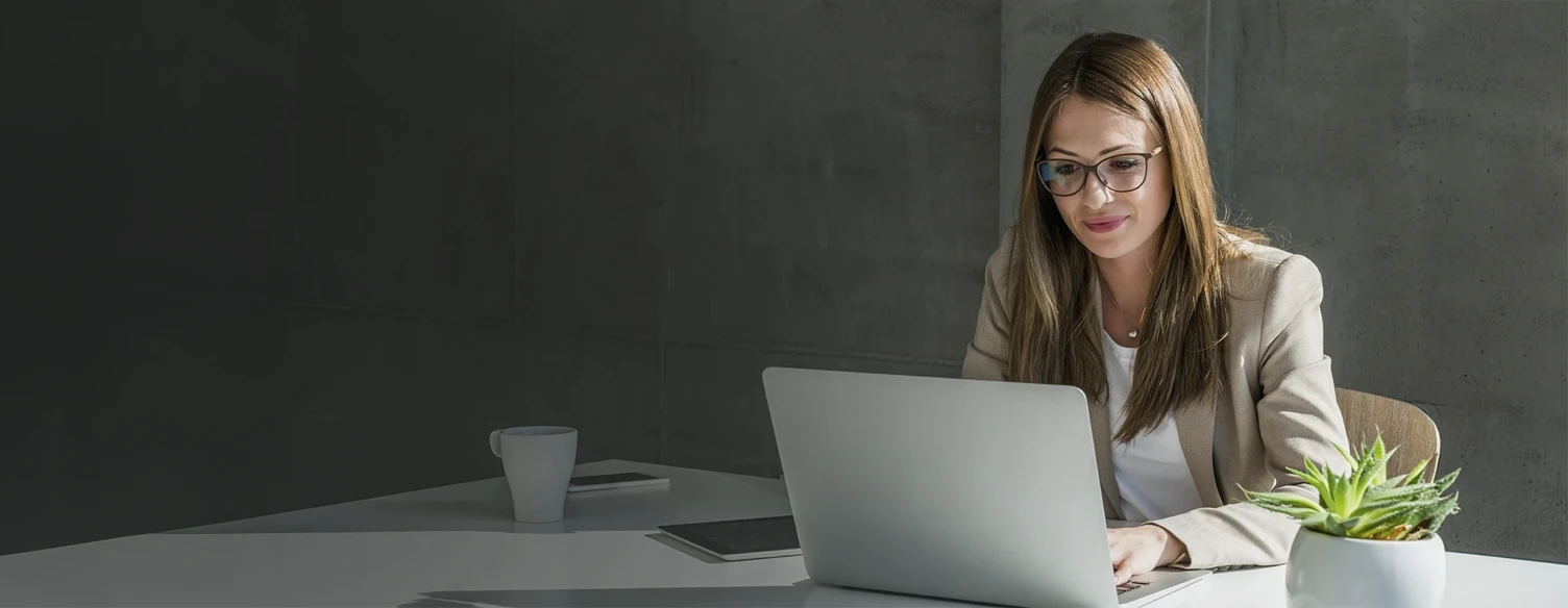 senhora sentada à secretária com computador, a trabalhar