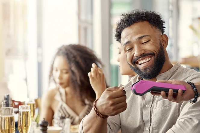 Man paying a bill at a restaurant, using a contactless card on a POS terminal
