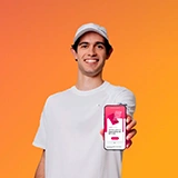 Nuno Borges de chapéu e t-shirt branca a mostrar o ecrã do seu telemóvel, com o pedido de cartão na App Millennium