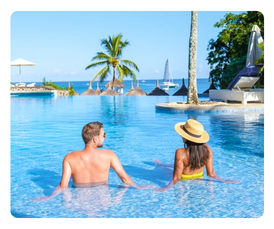Casal relaxa numa piscina infinita com vista para uma praia tropical